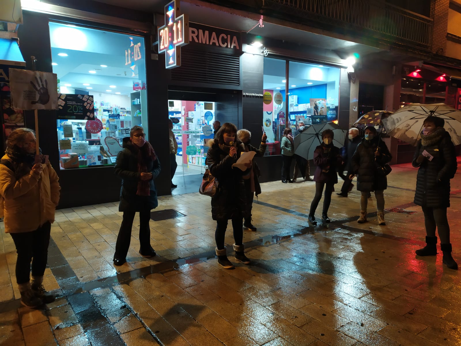 Varias personas en la Plaza del Carmen en círculo; está lloviendo. 